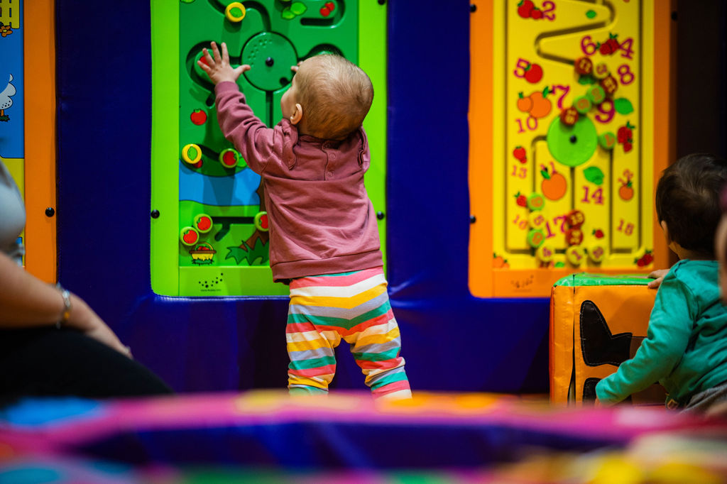 Little baby girl standing to play in the baby soft play area at High Rise Lisburn